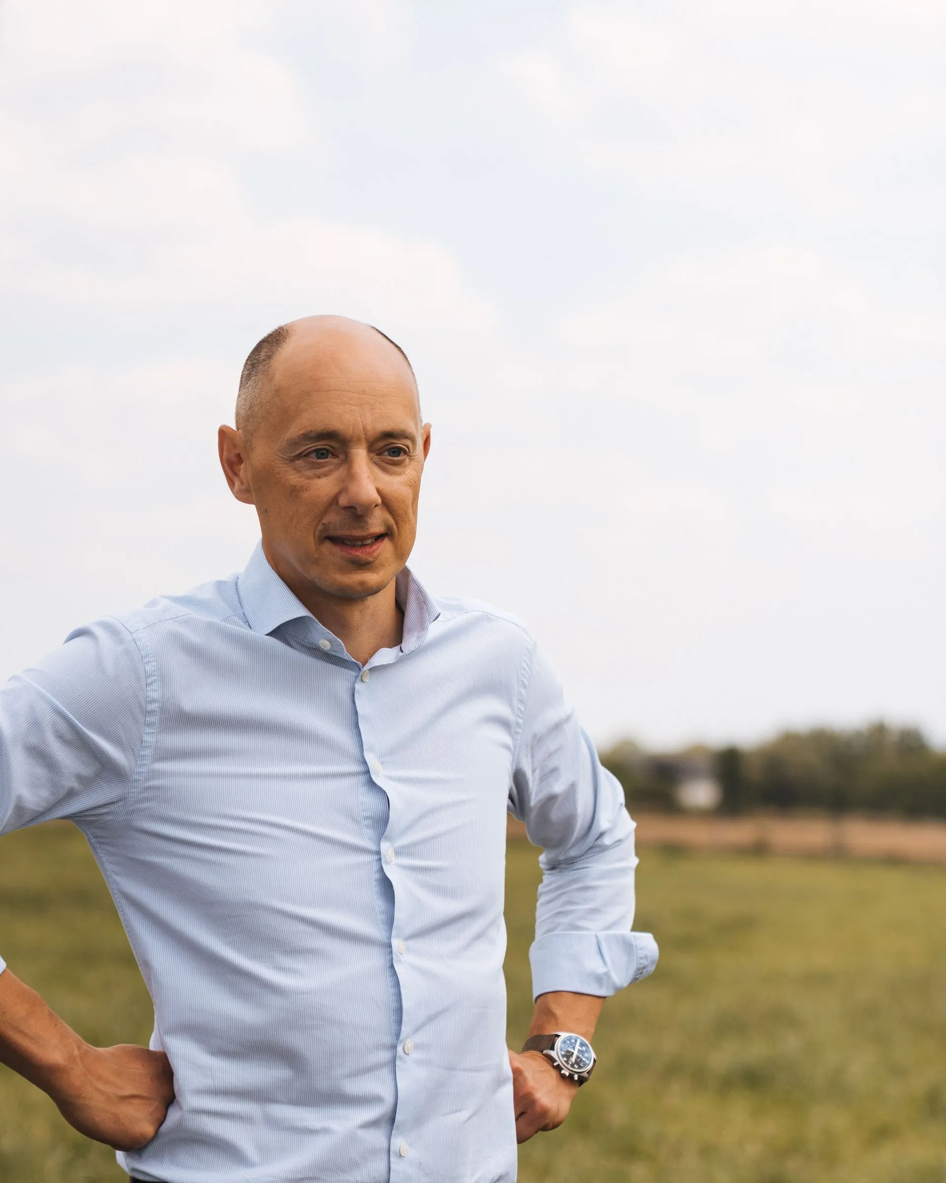 Arnaud Vandenbogaerde in een lichtblauw hemd in de weide, met de handen in de zij