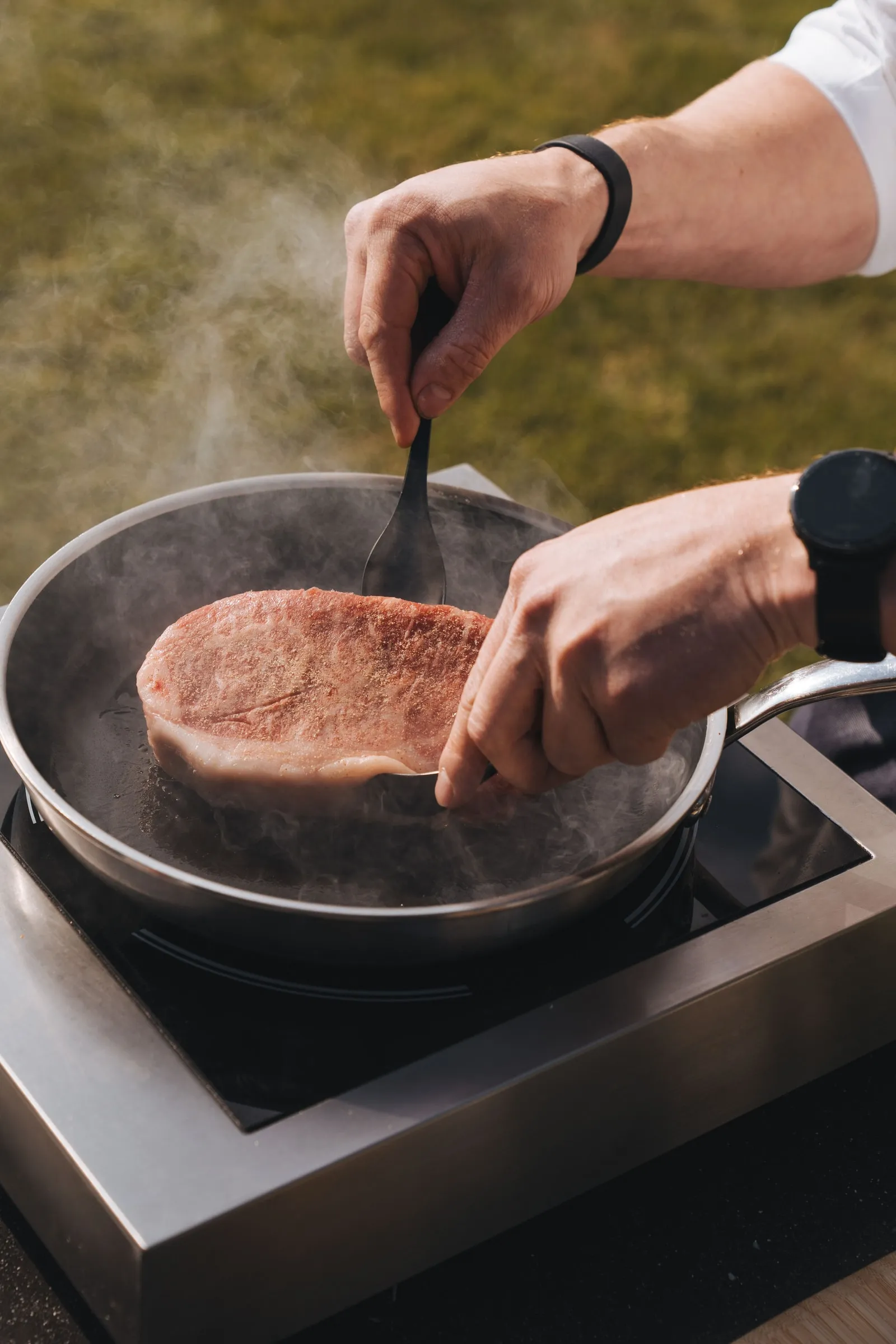Een chef legt een dikke steak van Tajiri in een dampende pan